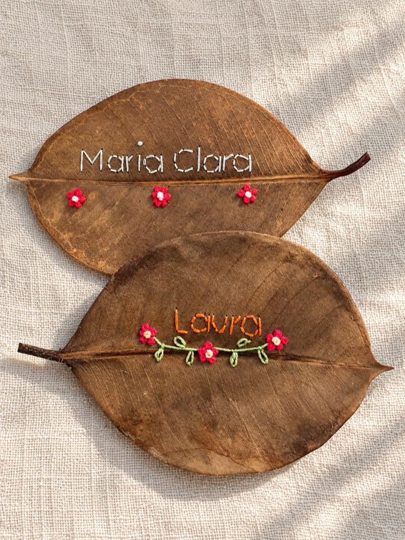 Folhas bordadas com os nomes Maria Clara e Laura